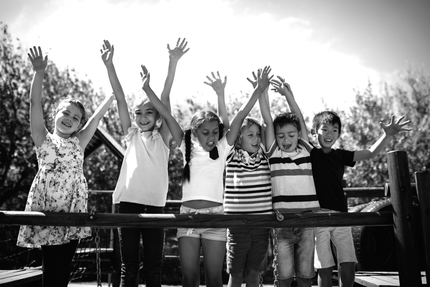 Group of kids cheering with hands raised on a playground